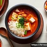 김치찌개 레시피로 유튜브 시작하기 - A vibrant and cozy kitchen scene featuring a steaming bowl of kimchi jjigae soup with visible chunks...